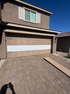 A garage door with new white panels installed, showing a repair or replacement job by Lifetime Garage Door in Las Vegas, NV.