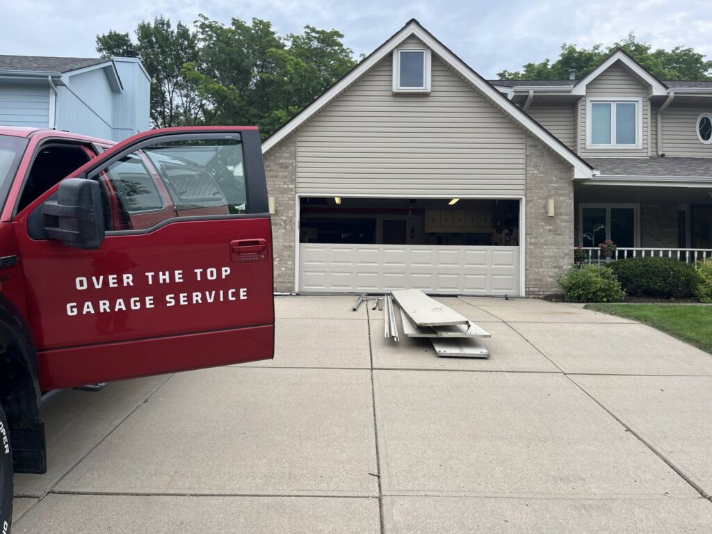 Garage door replacement in progress with old panels on the driveway and an Over The Top Garage Service truck in Albuquerque, NM.
