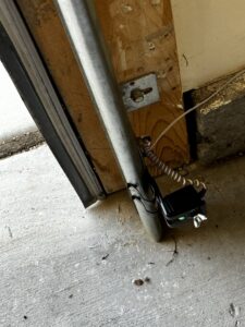 A close-up view of a garage door safety sensor installed near the floor by Apex Garage Doors LLC in Las Vegas, NV