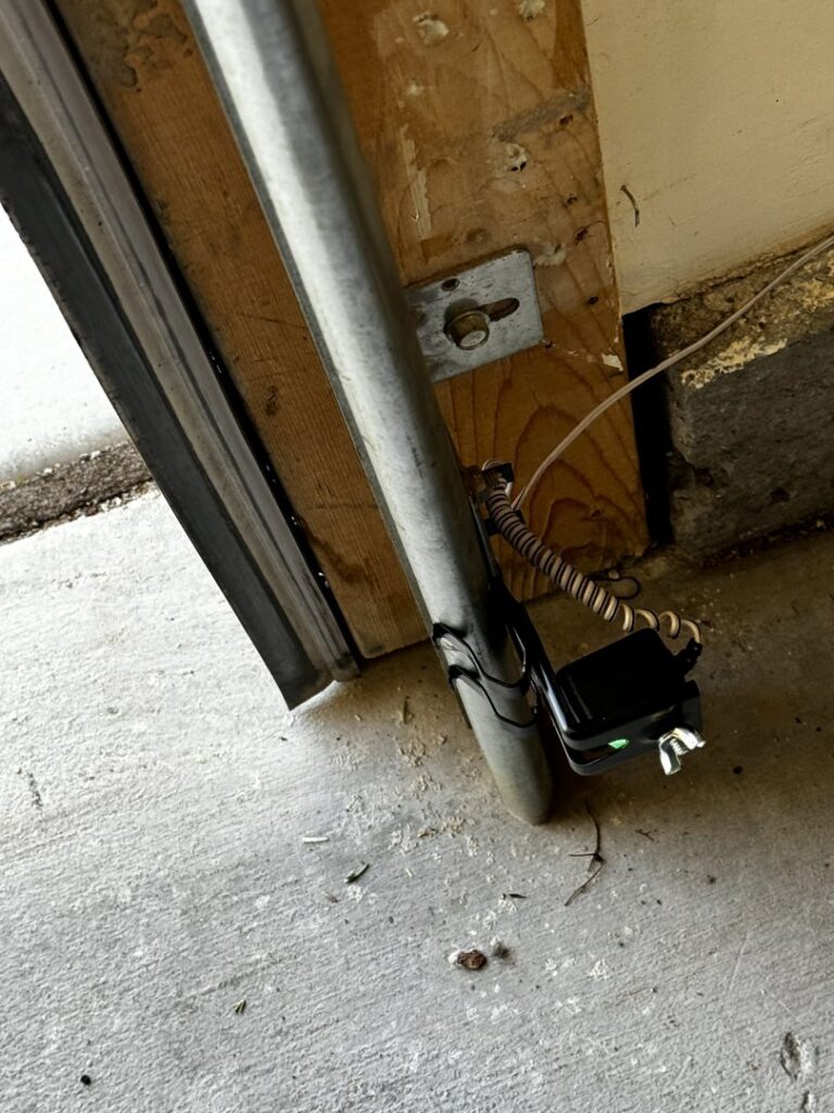 A close-up view of a garage door safety sensor installed near the floor by Apex Garage Doors LLC in Las Vegas, NV