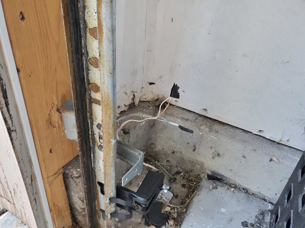 Close-up of a garage door safety sensor being installed or inspected by Sandia Garage Door Repair in Albuquerque, NM