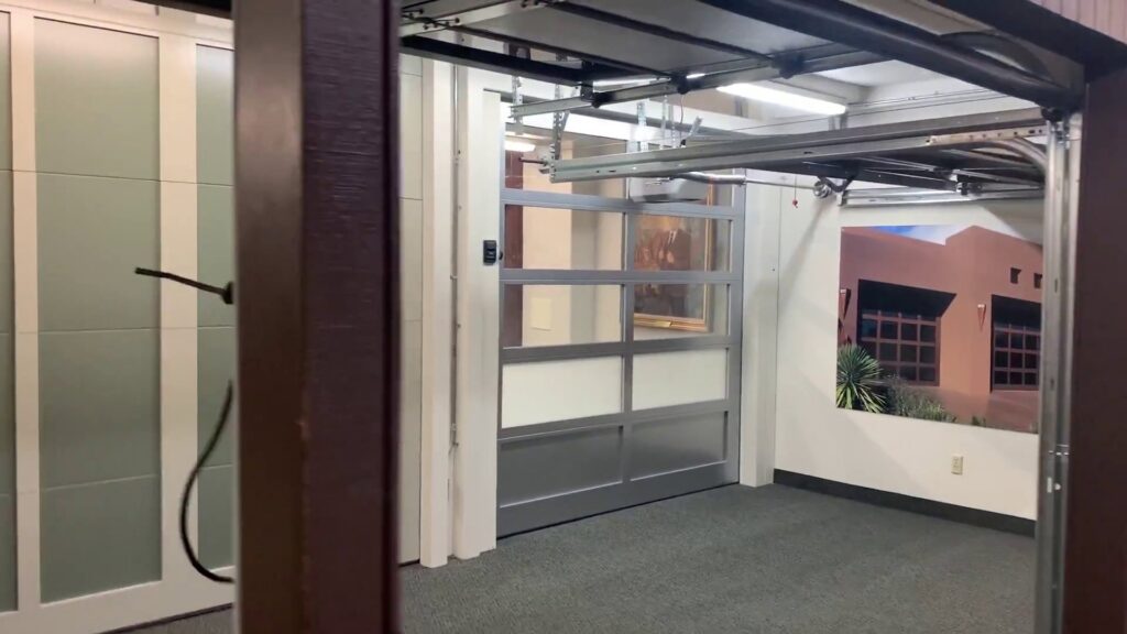 Interior view of a garage door showroom displaying various door styles, including a modern glass door, at Garage Door Store Boise, ID.