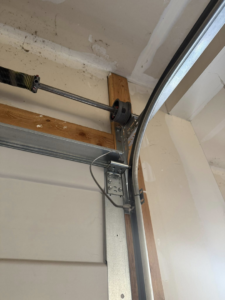 A close-up view of a garage door torsion spring, cable drum, and track system by A-1 Garage Door Repair in Syracuse, UT.