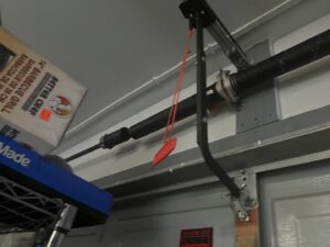 Close-up of a garage door torsion spring assembly and track, serviced by Norman's Overhead Doors, Inc. in Mililani Town, HI.