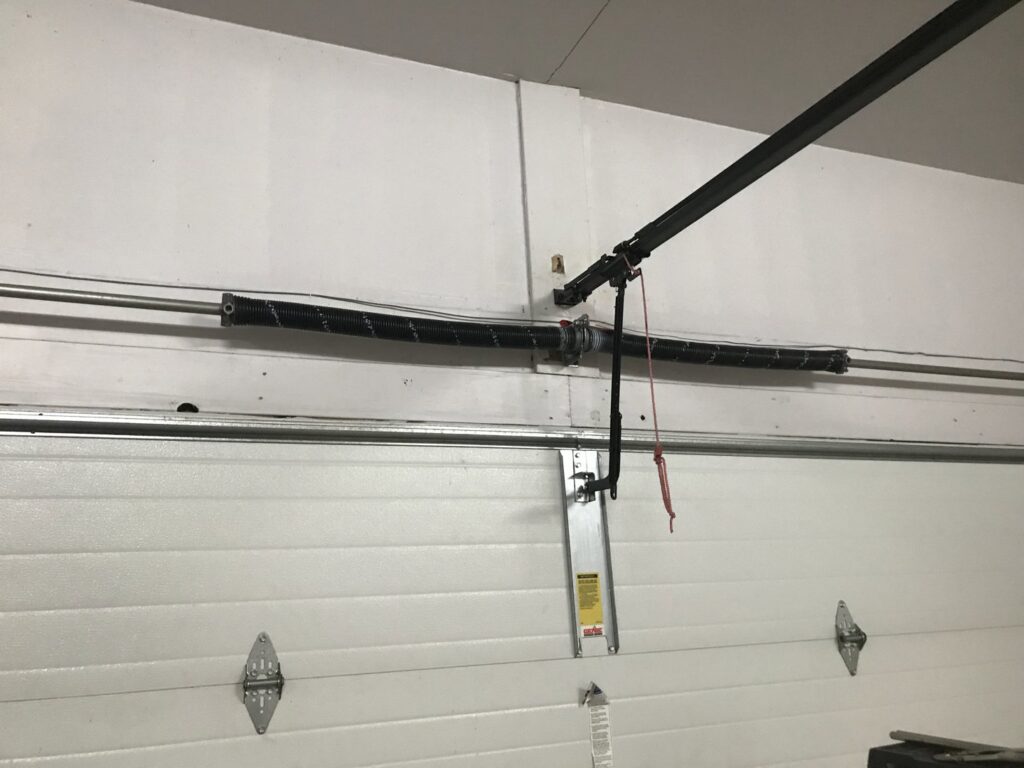 Close-up of a garage door torsion spring system, indicating repair or installation by Up N Over Garage Doors LLC in Layton, UT.
