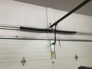 Close-up of a garage door torsion spring system, indicating repair or installation by Up N Over Garage Doors LLC in Layton, UT.