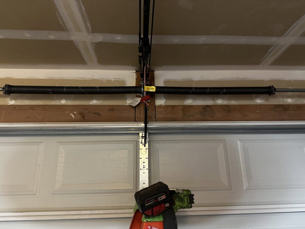 A close-up view of a garage door torsion spring system, indicating repair or maintenance by Apex Garage Doors LLC in Las Vegas, NV