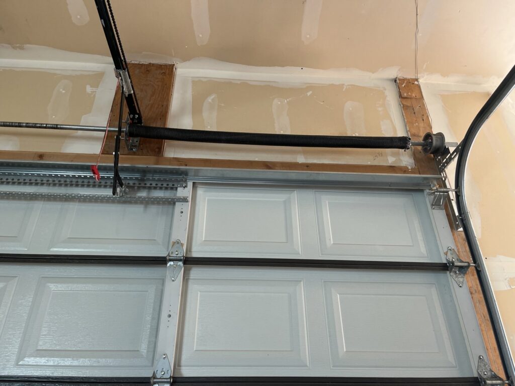 Close-up view of a garage door's torsion spring system and tracks, indicating repair or installation work by Right Choice Doors in Layton, UT.