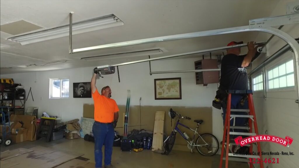 Two technicians installing garage door tracks and an opener for Overhead Door of Sierra Nevada in Reno, NV.