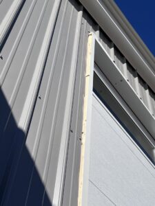 A close-up view of a garage door's vertical track and weather stripping, showcasing installation detail by Overhead Door Company of Santa Fe in Santa Fe, NM.