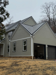 View of the garage side of a home with new light green siding and dark garage doors installed by CRD Builders in Hamilton Township, NJ.