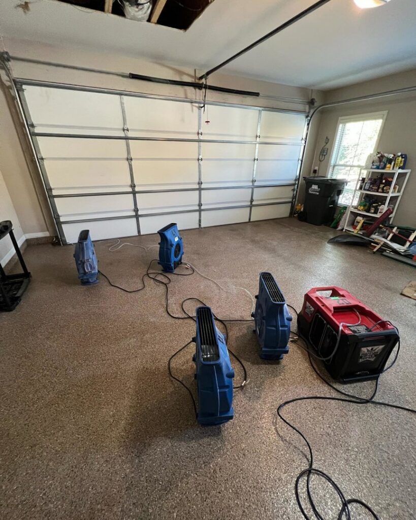 Water damage drying equipment, including air movers and a dehumidifier, set up in a garage by Sentry Restoration in Volo, IL