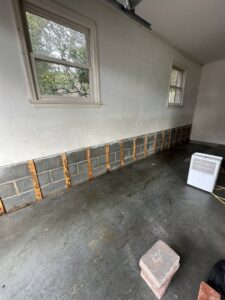 Water damage remediation in a garage with drywall removed and a dehumidifier, performed by PuroClean of Lancaster in Lancaster, PA.