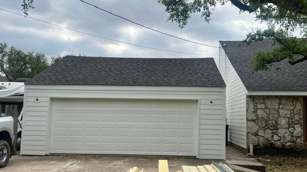 A garage featuring newly installed white horizontal siding, a quality job by Ideal Siding Austin in Austin, TX.
