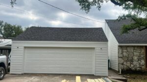 A garage featuring newly installed white horizontal siding, a quality job by Ideal Siding Austin in Austin, TX.