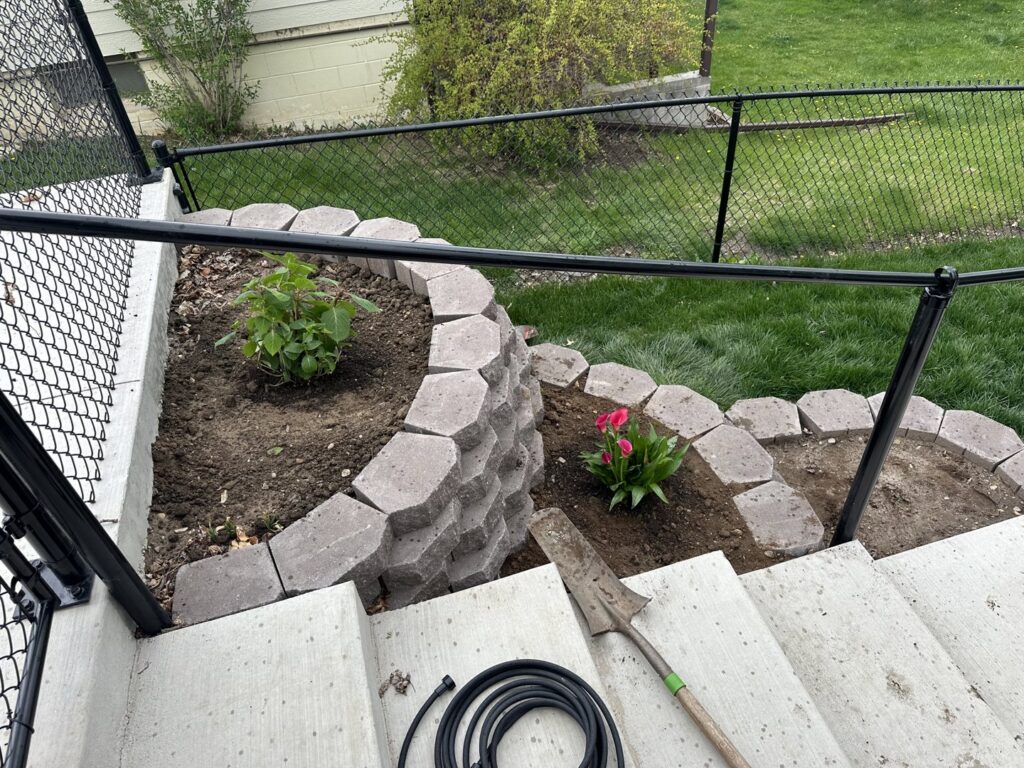 A newly planted garden bed with decorative retaining blocks, showcasing landscaping services by Matt's Lawn Service in Casper, WY.