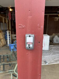 A Genie garage door opener button installed on a red post by Precision Garage Door Service of NC in Morrisville, NC.