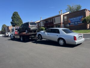 Giner's Towing performing a double tow with an SUV on the flatbed and a sedan by its rear wheels in Aurora, CO.