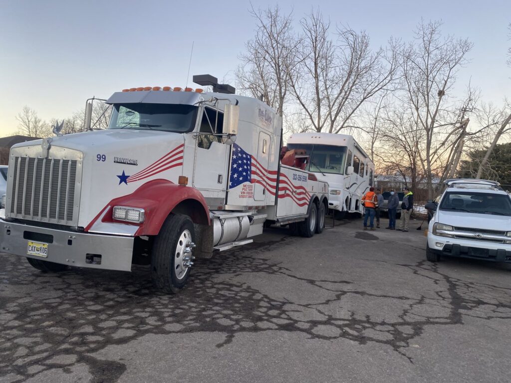 Giner's Towing heavy-duty tow truck preparing to tow a large RV in Aurora, CO.