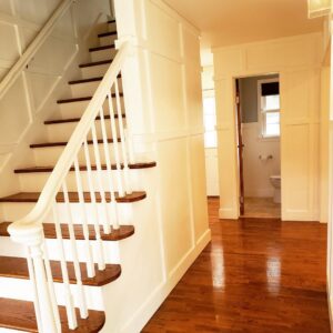 A gleaming entryway with polished hardwood floors, white wainscoting, and a staircase, cleaned by A To Zen in Lansing, MI.