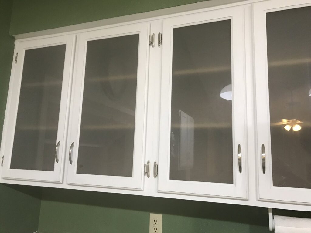 Gleaming white kitchen cabinets with glass inserts, showcasing the detailed house cleaning services of A Clean Xscape LLC in Chandler, AZ.
