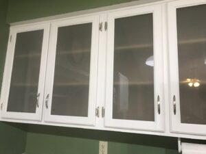 Gleaming white kitchen cabinets with glass inserts, showcasing the detailed house cleaning services of A Clean Xscape LLC in Chandler, AZ.