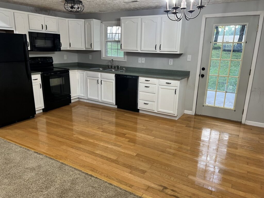 A gleaming kitchen with white cabinets and polished hardwood floors, cleaned by Treadway's Cleaning Services in Spencer, IN