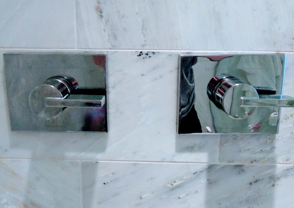 Gleaming shower fixtures on a marble wall, showcasing the meticulous cleaning by Jessie Clean in Indianapolis, IN.