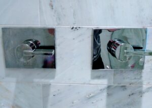Gleaming shower fixtures on a marble wall, showcasing the meticulous cleaning by Jessie Clean in Indianapolis, IN.