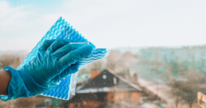 A gloved hand cleaning a window, demonstrating professional house cleaning by ABF Professional Cleaning Inc in Jackson, WY.