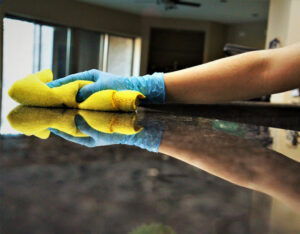 A gloved hand wiping down a shiny countertop, demonstrating cleaning services by House Cleaning Solutions in Mesa, AZ.