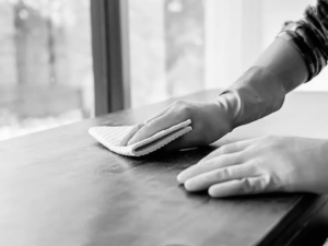 A gloved hand wiping a wooden surface, demonstrating cleaning by EE Cleaning and Restoration in Colorado Springs, CO.