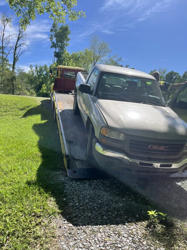 A grey GMC pickup truck being loaded onto a flatbed tow truck by Glenn's Towing & Recovery Inc in Lafayette, LA.