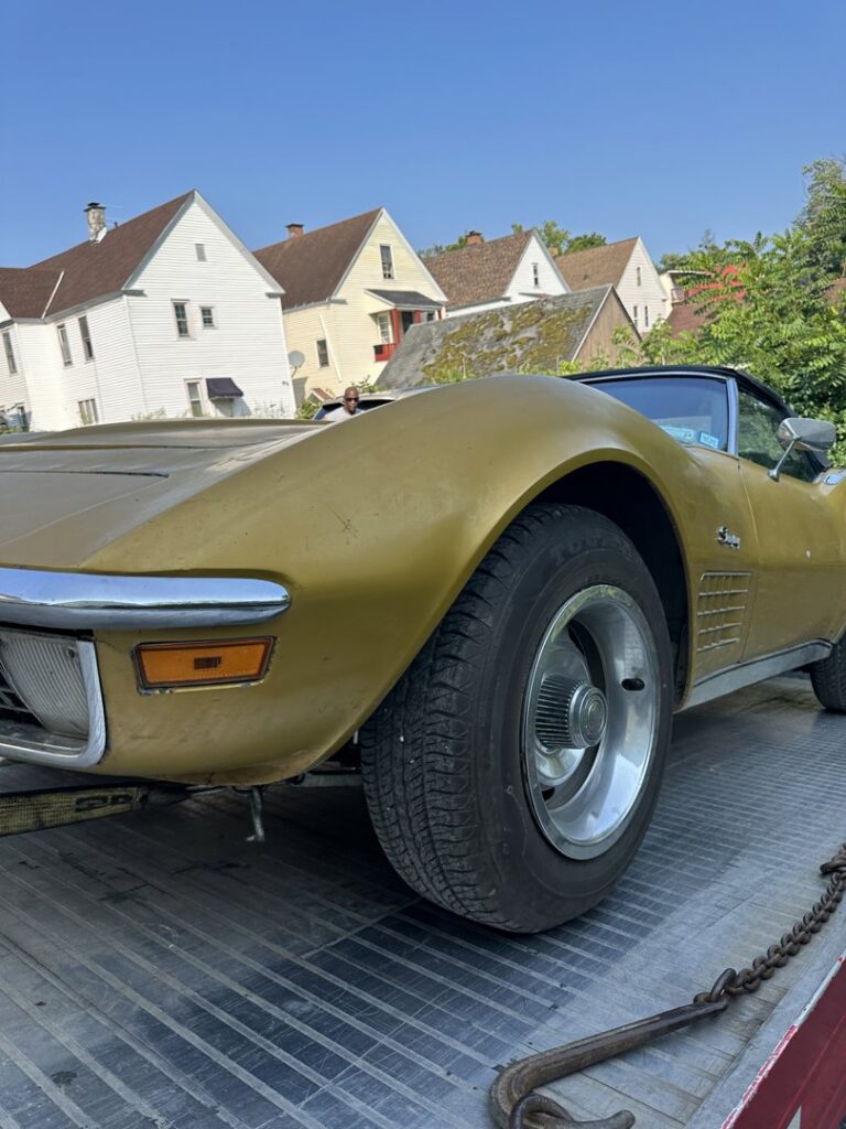 A gold classic car being transported on a flatbed tow truck by RonniesTowing&Recovery in Bryan, TX