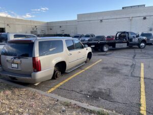 A gold SUV missing its rear wheels being prepared for towing by Black Mamba Towing & Recovery Llc in Aurora, CO.