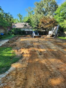 Graded land with excavators in the background, showing site preparation by East Shelby Demolition & Pool Removal in Olive Branch, MS.