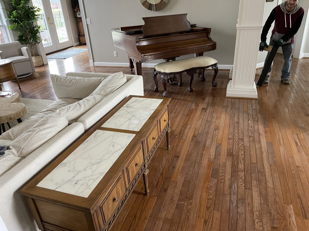 A grand piano in a residential living room with a mover preparing for transport by Peroulas Moving and Storage in Knoxville, TN