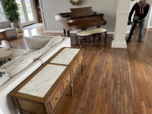 A grand piano in a residential living room with a mover preparing for transport by Peroulas Moving and Storage in Knoxville, TN