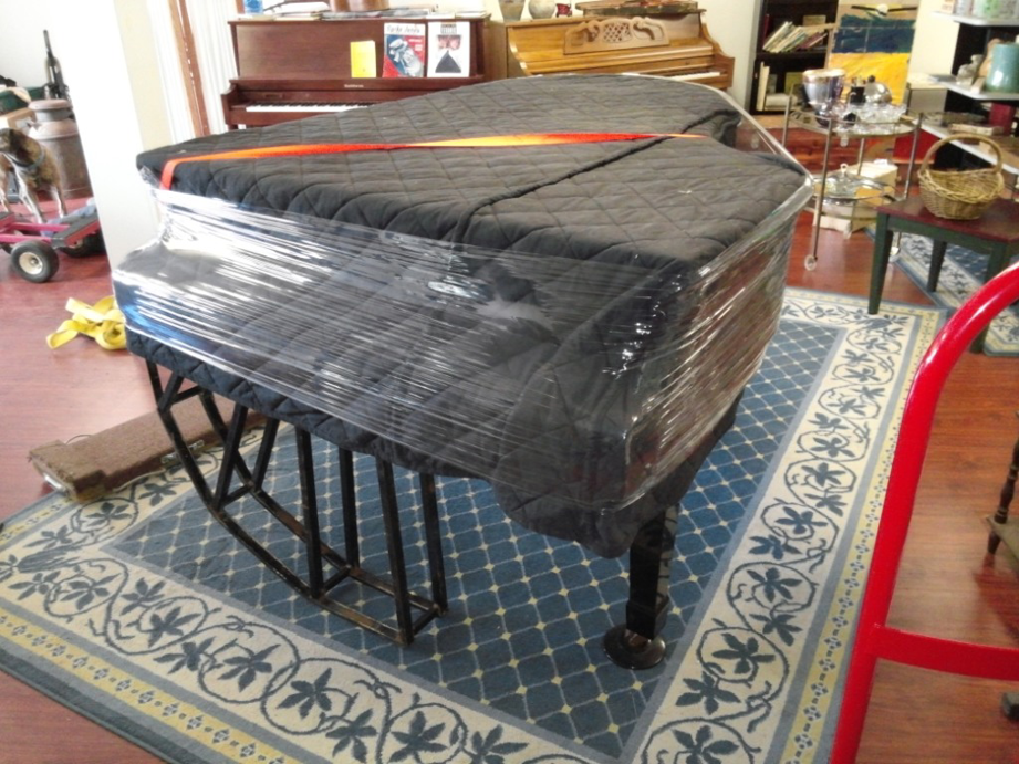 A grand piano carefully wrapped in moving blankets and plastic, ready for transport by All Around Town Movers in Memphis, TN.