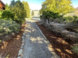 A well-maintained gravel pathway bordered by fresh mulch and healthy shrubs, showcasing landscaping by Jerman Lawn Care in Bozeman, MT.