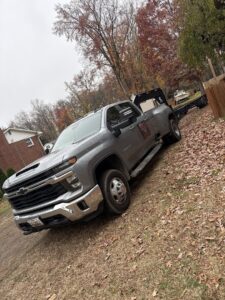 A gray Chevrolet dually pickup truck with a flatbed trailer, ready for towing services from A+1 Towing Service in Middle River, MD.