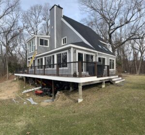 A house with new gray horizontal siding and a large deck, completed by Atlantic Roofing and Siding in East Hartford, CT.