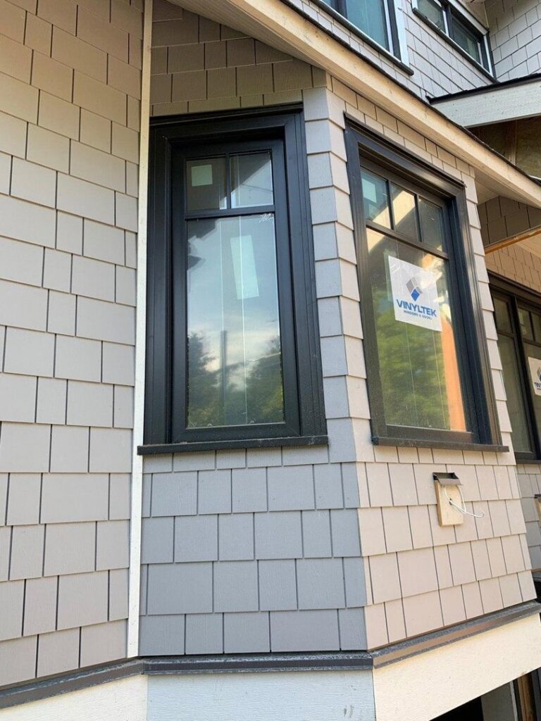 Gray shake siding installation around black windows on a home by Ideal Siding Dallas, TX.