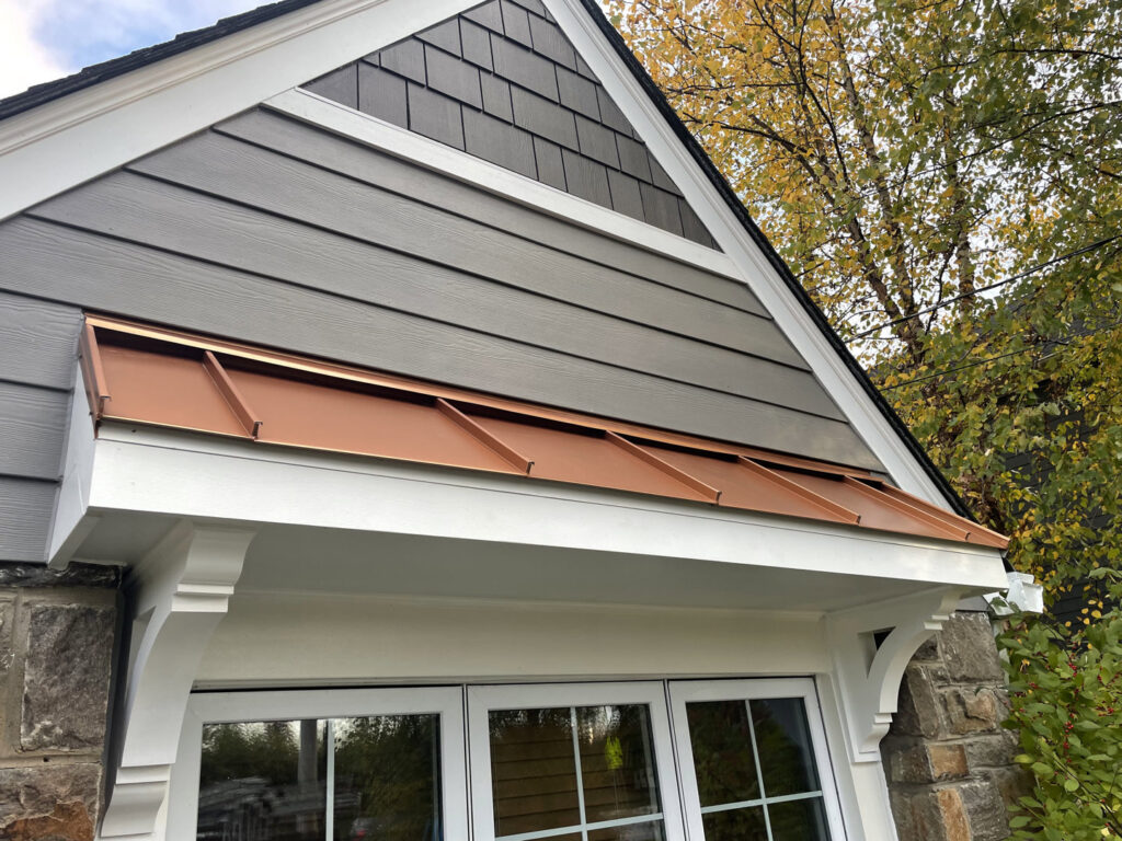 House exterior featuring gray horizontal siding, shake siding in the gable, and a decorative copper awning by High Quality Exteriors in Rockville, MD.