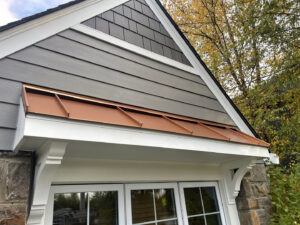 House exterior featuring gray horizontal siding, shake siding in the gable, and a decorative copper awning by High Quality Exteriors in Rockville, MD.