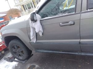 A gray SUV with its front wheels on a tow dolly in a snowy environment, indicating a towing service by Buffalo Towing Services in Buffalo, NY.