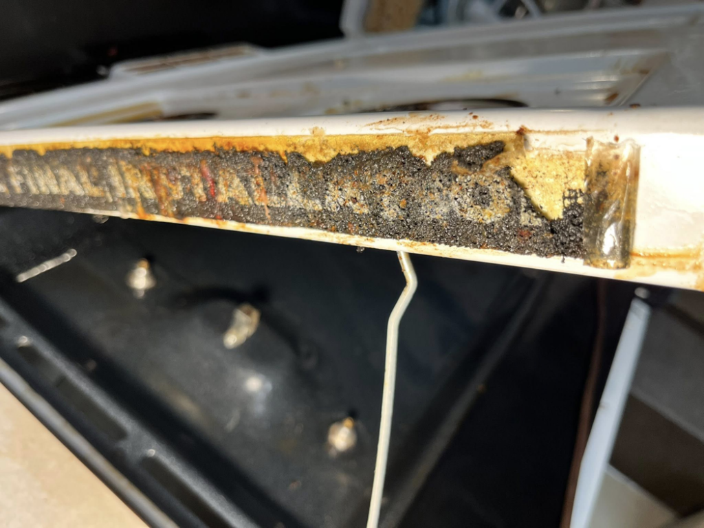 A very greasy and dirty oven edge, showing accumulated grime before professional cleaning by Masters Touch Cleaning Solutions LLC.