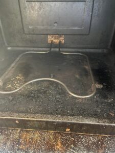 A very greasy oven interior with burnt-on food residue, showing a challenging cleaning task for Skedaddle Cleaning Services in Eufaula, AL.