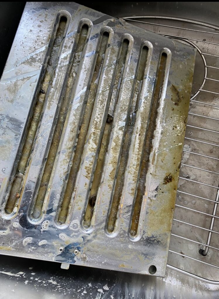 A greasy and dirty range hood vent cover before professional cleaning by Cuse Cleaning in Syracuse, NY.