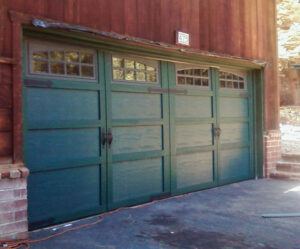 A green carriage-style garage door with windows and decorative hardware installed by Overhead Door of Sierra Nevada in Reno, NV.